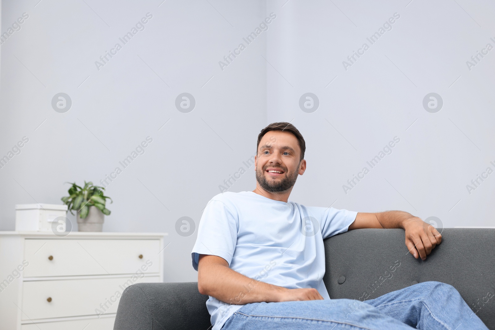 Photo of Happy man resting on sofa at home