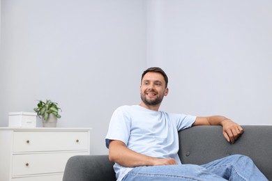Photo of Happy man resting on sofa at home