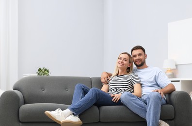 Photo of Happy couple spending time together on sofa at home. Space for text