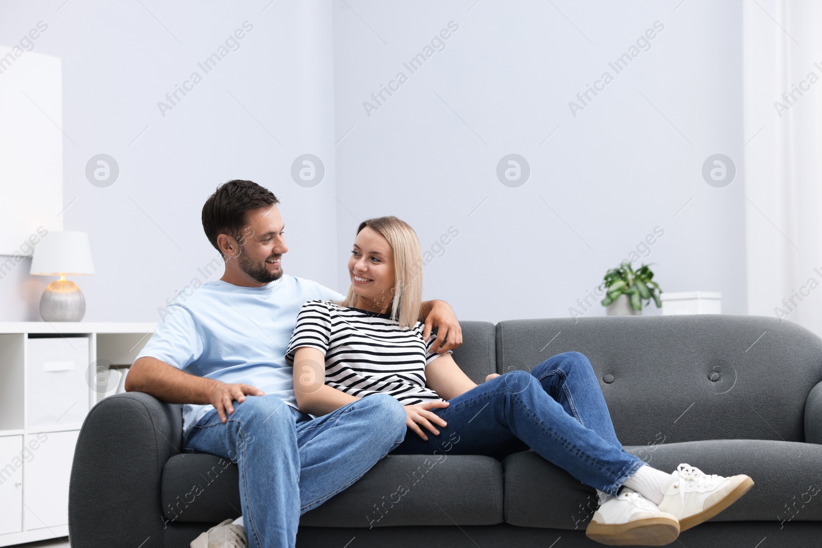 Happy couple spending time together on sofa at home. Space for text Photo of Happy couple spending time together on sofa at home. Space for text