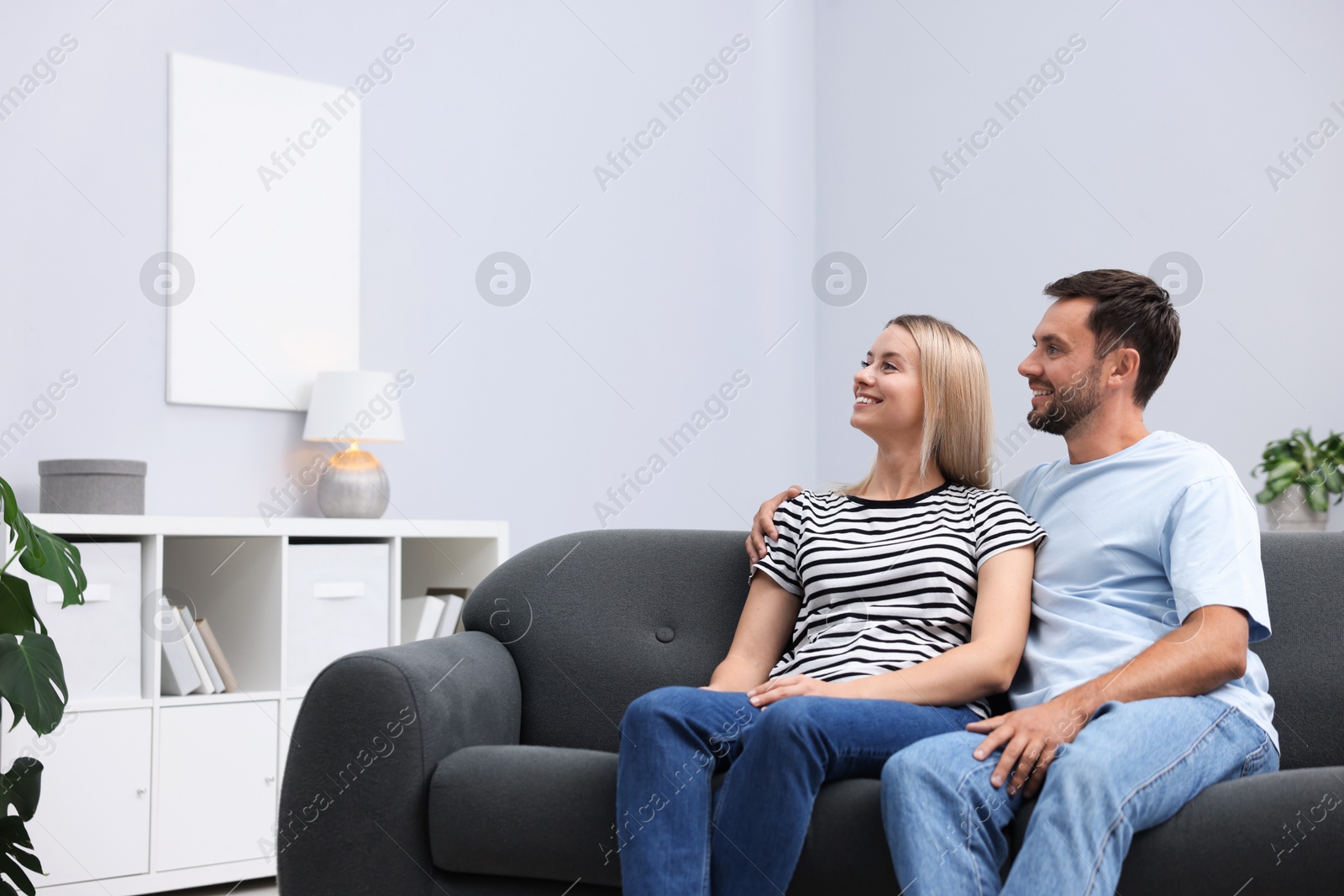 Photo of Happy couple spending time together on sofa at home. Space for text