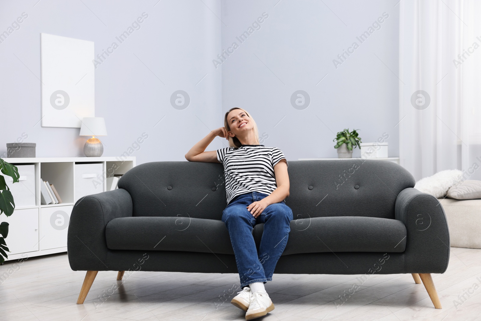 Photo of Happy woman resting on sofa at home