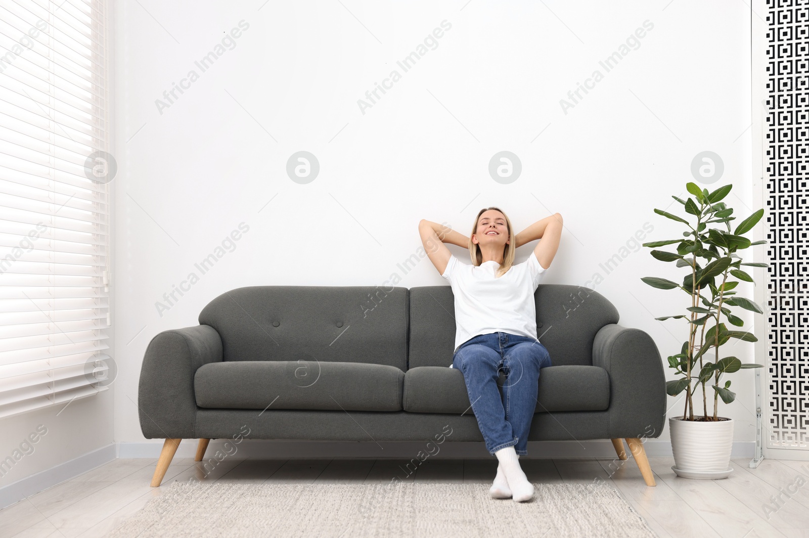 Photo of Happy woman resting on sofa at home. Space for text