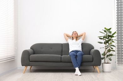 Photo of Happy woman resting on sofa at home. Space for text