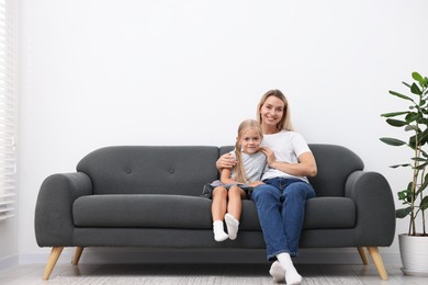 Photo of Mother and daughter spending time together on sofa at home. Space for text