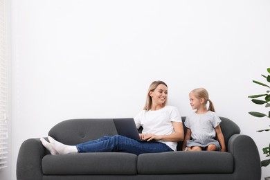Photo of Mother and daughter spending time together on sofa at home. Space for text