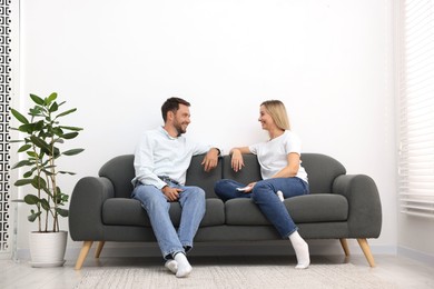 Photo of Couple with air conditioner remote control on sofa at home