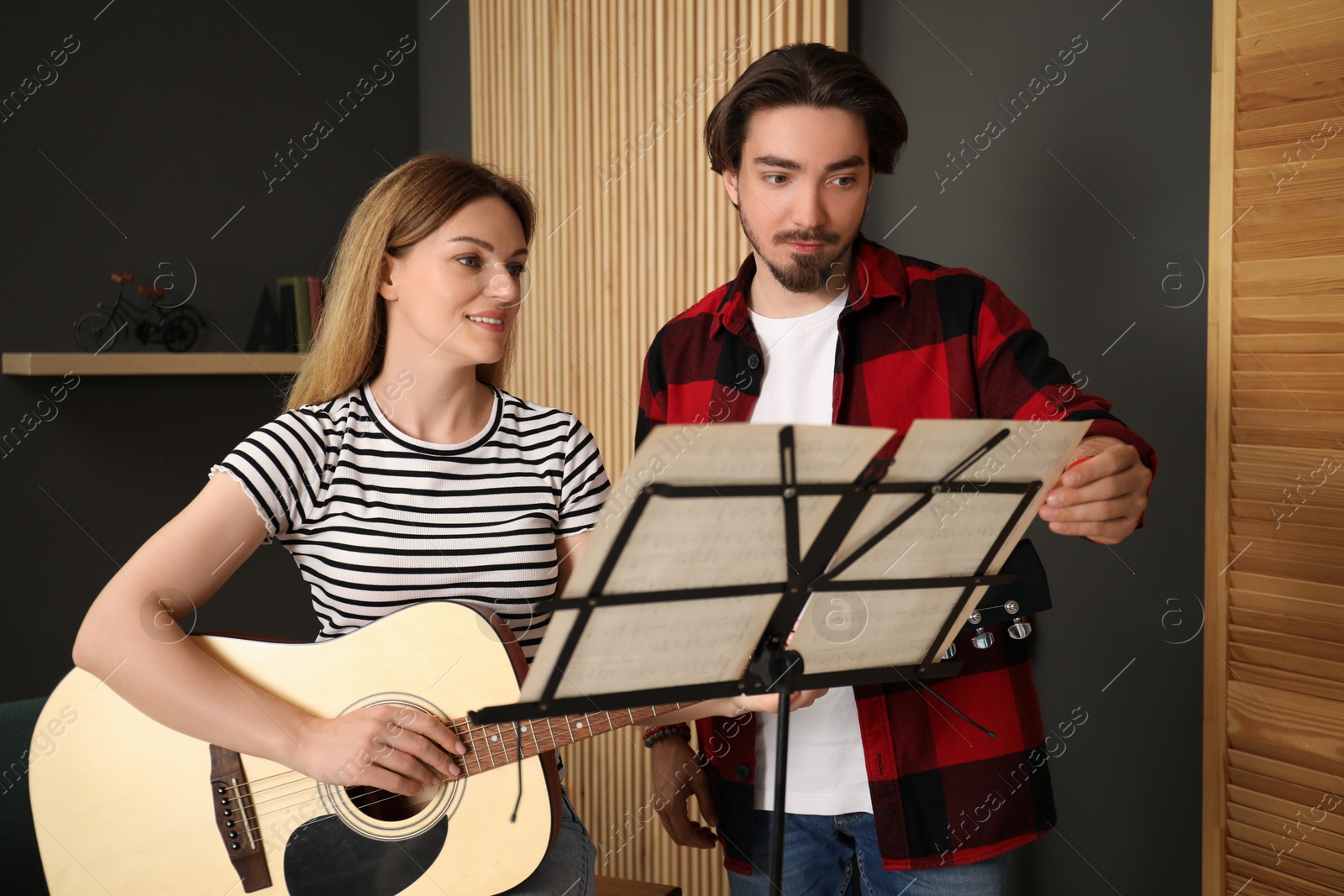 Photo of Tutor teaching woman to play guitar indoors