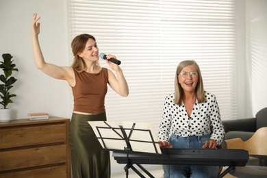 Photo of Woman learning to sing while her teacher accompanying on piano indoors