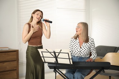 Photo of Woman learning to sing while her teacher accompanying on piano indoors
