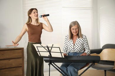 Photo of Woman learning to sing while her teacher accompanying on piano indoors