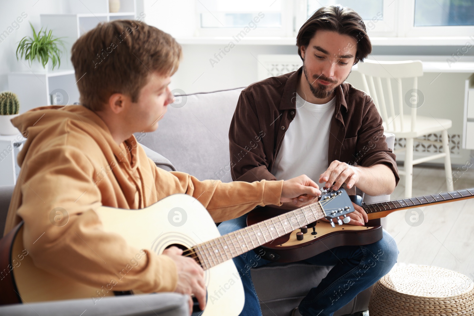 Photo of Tutor teaching man to play guitar at home