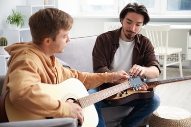 Photo of Tutor teaching man to play guitar at home