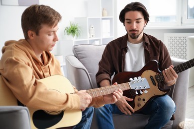 Photo of Tutor teaching man to play guitar at home