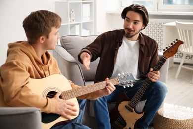 Photo of Tutor teaching man to play guitar at home