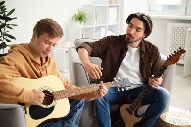 Photo of Tutor teaching man to play guitar at home