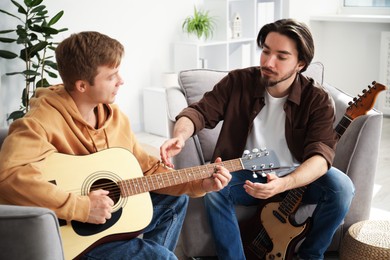 Photo of Tutor teaching man to play guitar at home