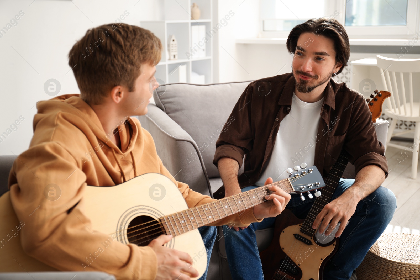 Photo of Tutor teaching man to play guitar at home
