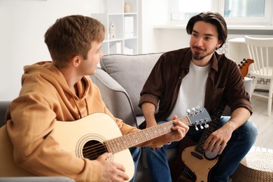 Photo of Tutor teaching man to play guitar at home