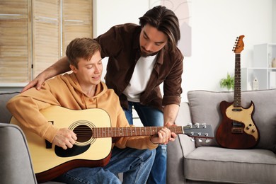 Photo of Tutor teaching man to play guitar at home