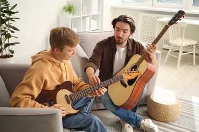 Photo of Tutor teaching man to play guitar at home