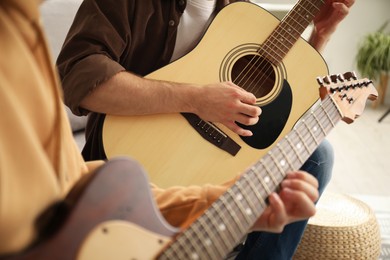 Photo of Tutor teaching man to play guitar at home, closeup
