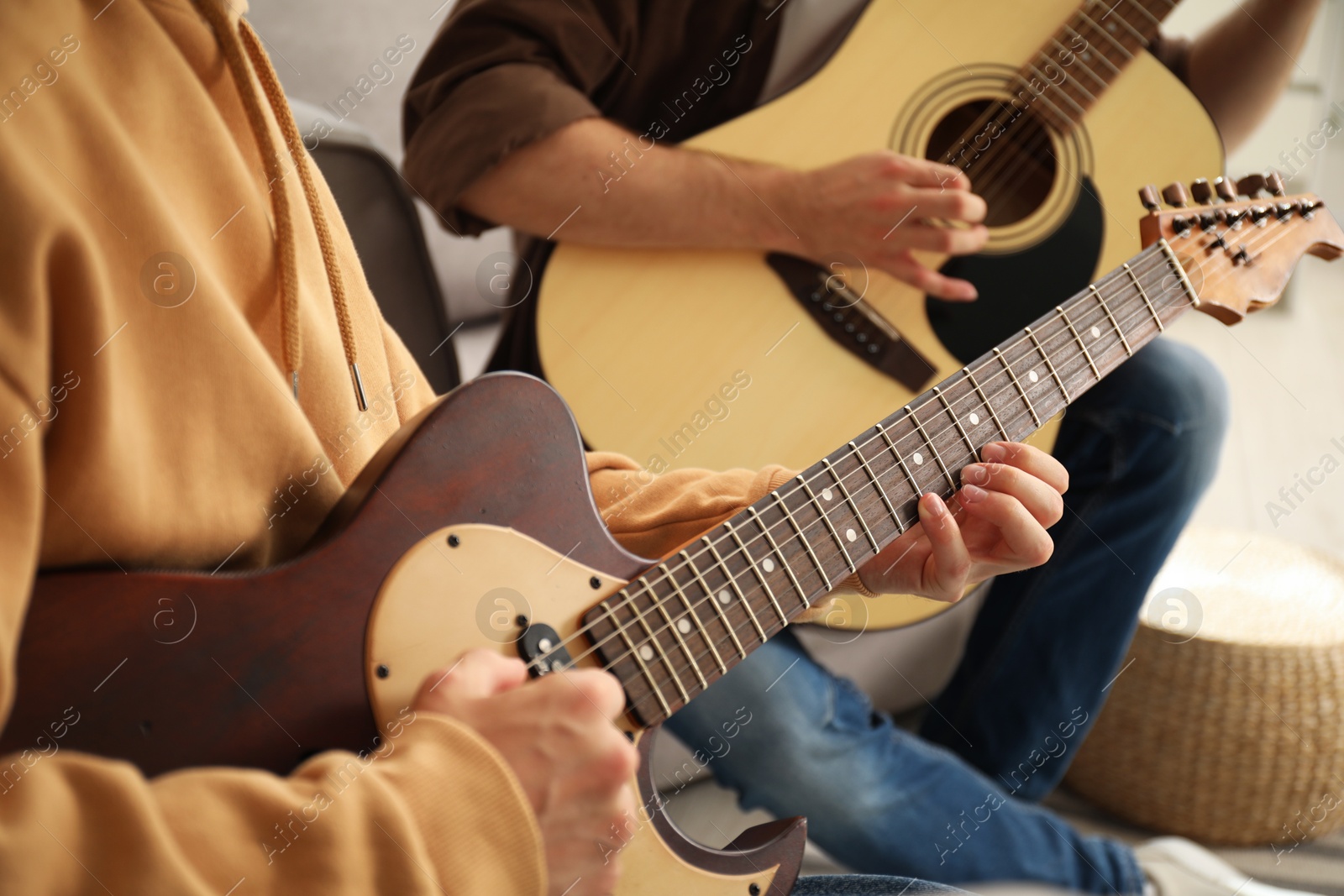 Photo of Tutor teaching man to play guitar at home, closeup