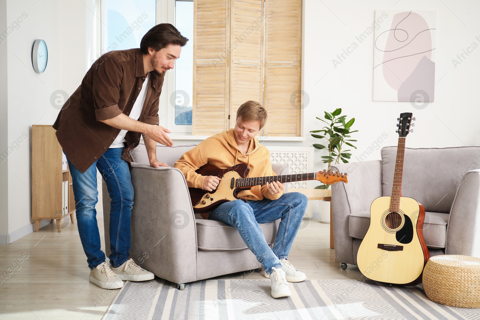 Photo of Tutor teaching man to play guitar at home