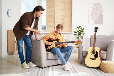 Photo of Tutor teaching man to play guitar at home