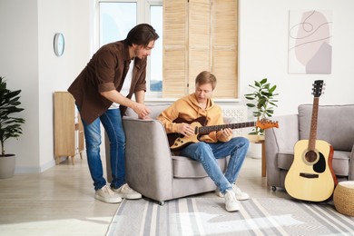 Photo of Tutor teaching man to play guitar at home