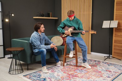 Photo of Tutor teaching man to play guitar indoors