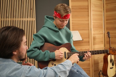 Photo of Tutor teaching man to play guitar indoors