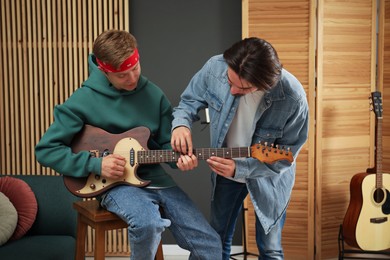 Photo of Tutor teaching man to play guitar indoors