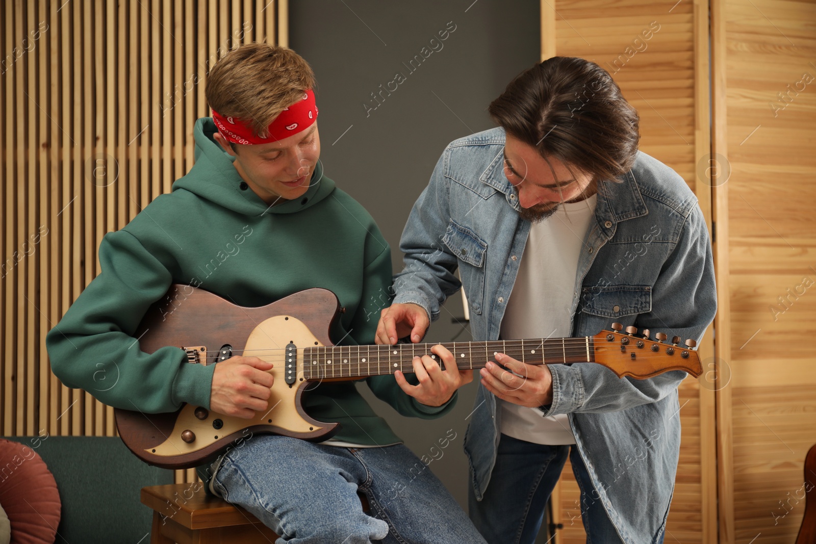 Photo of Tutor teaching man to play guitar indoors