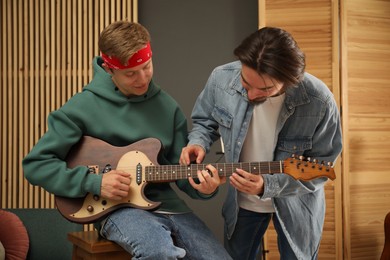 Photo of Tutor teaching man to play guitar indoors