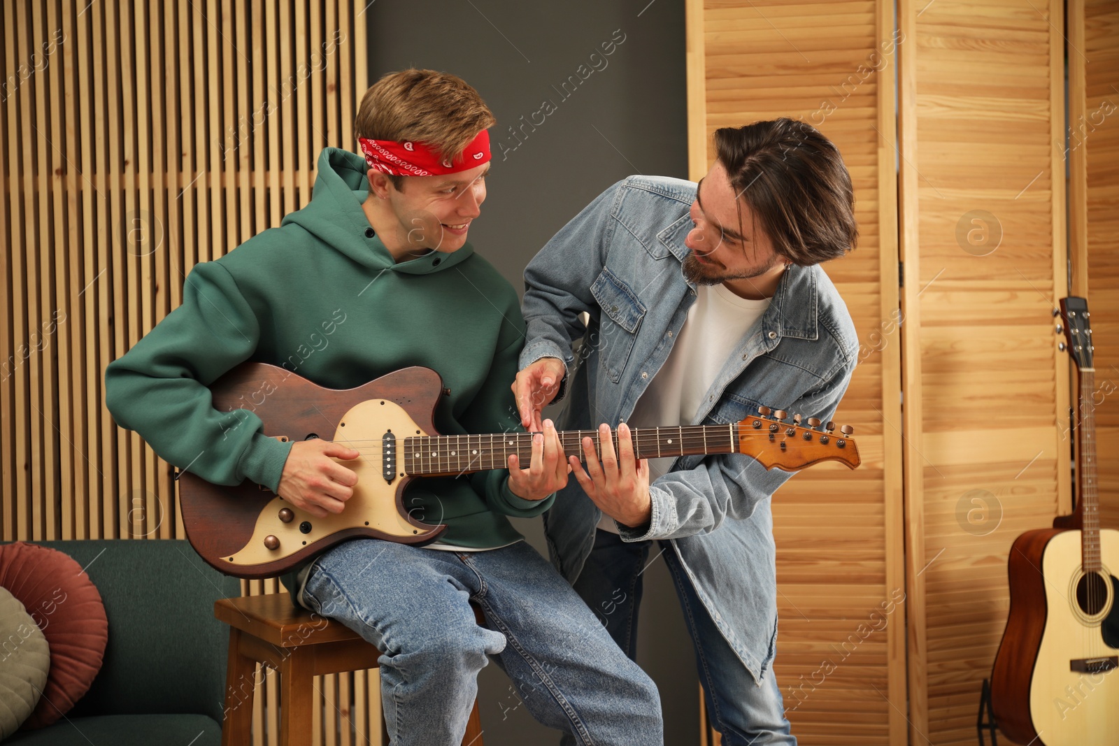 Photo of Tutor teaching man to play guitar indoors