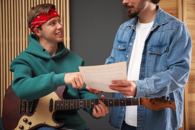 Photo of Tutor teaching man to play guitar at home, closeup