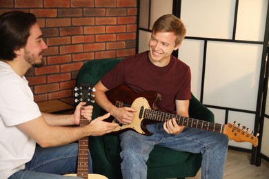 Photo of Tutor teaching man to play guitar indoors