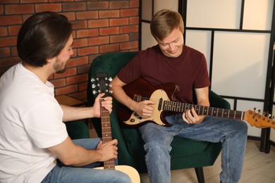 Photo of Tutor teaching man to play guitar indoors