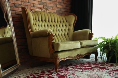 Photo of Green retro sofa, mirror and houseplant in room. Interior design