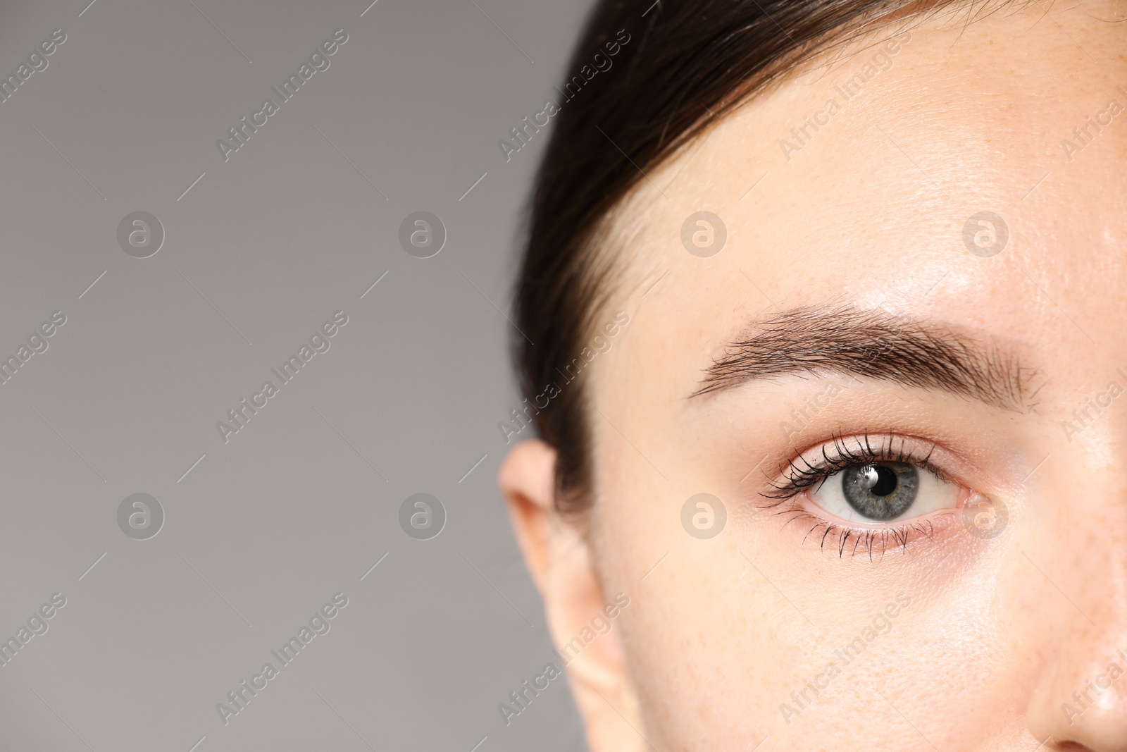 Photo of Woman with beautiful eyes on light grey background, closeup. Space for text