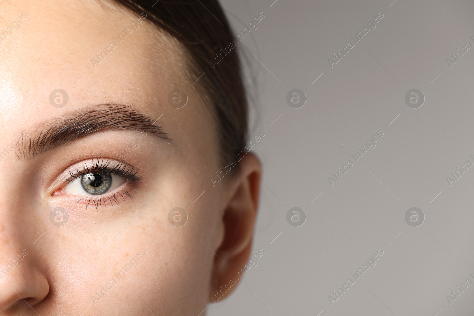 Photo of Woman with beautiful eyes on light grey background, closeup. Space for text