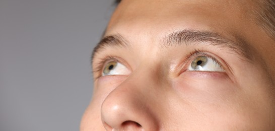 Photo of Man with beautiful eyes on light grey background, closeup. Space for text