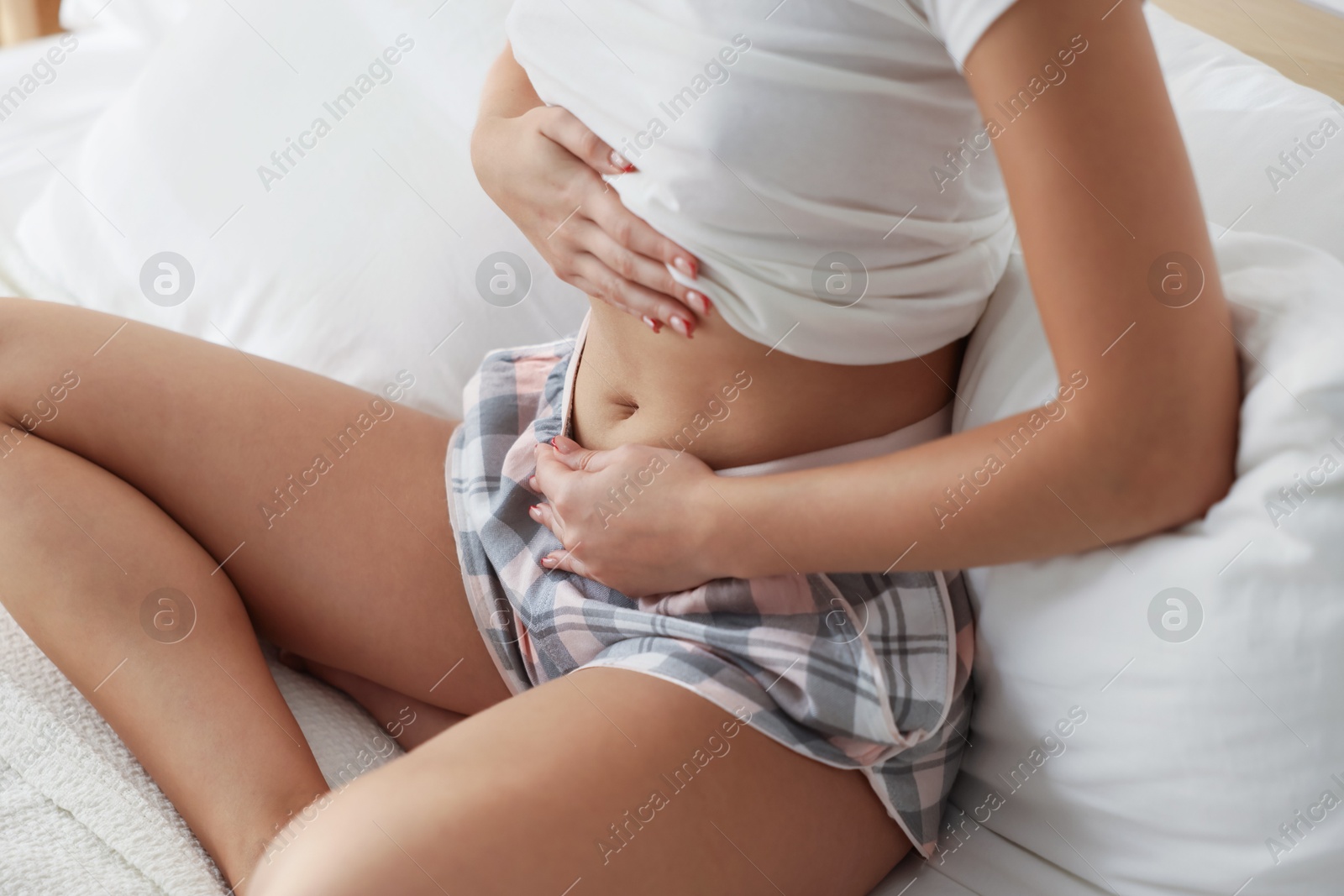 Photo of Young woman with flat belly on bed at home, closeup
