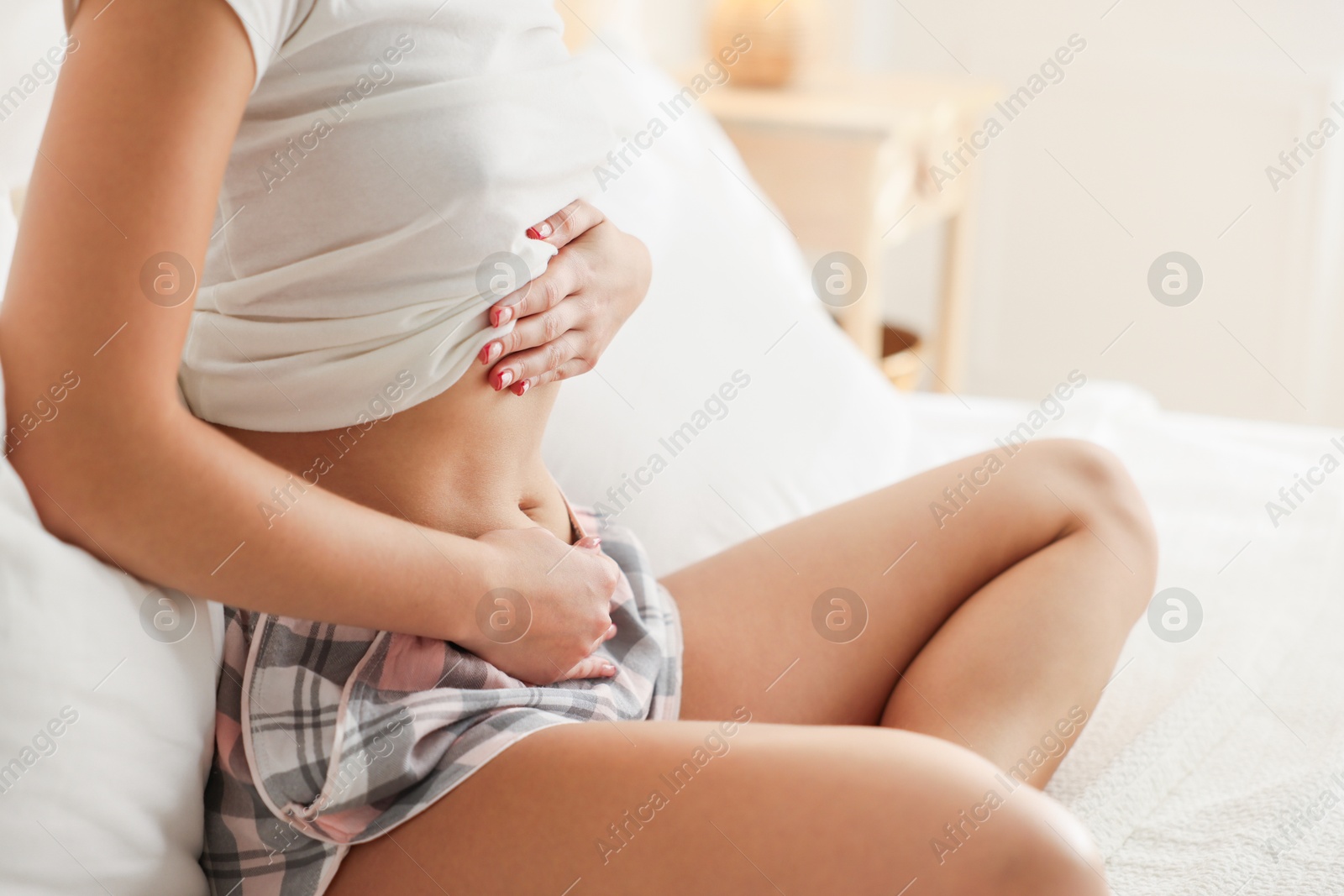 Photo of Young woman with flat belly on bed at home, closeup