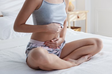 Photo of Young woman with flat belly on bed at home, closeup