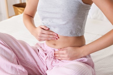 Photo of Young woman with flat belly on bed at home, closeup