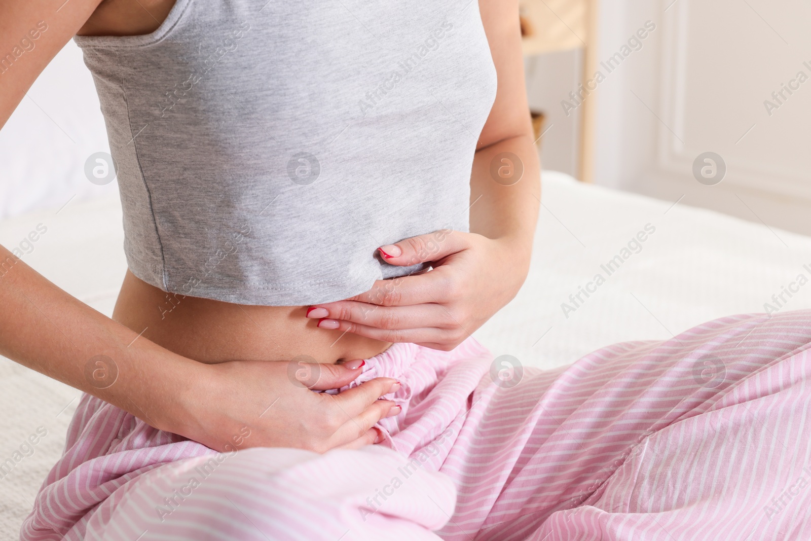 Photo of Young woman with flat belly on bed at home, closeup