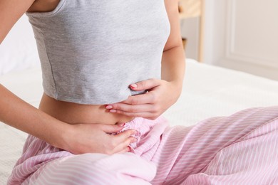 Photo of Young woman with flat belly on bed at home, closeup
