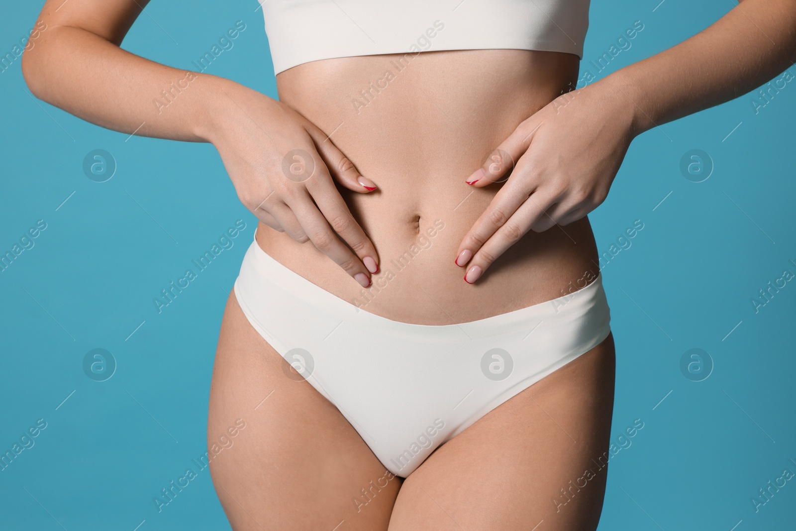 Photo of Young woman with flat belly on light blue background, closeup
